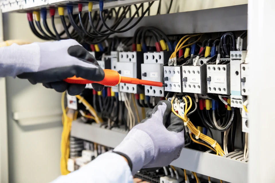 Technicien en combinaison de sécurité et casque blanc travaillant sur installation électrique résidentielle
